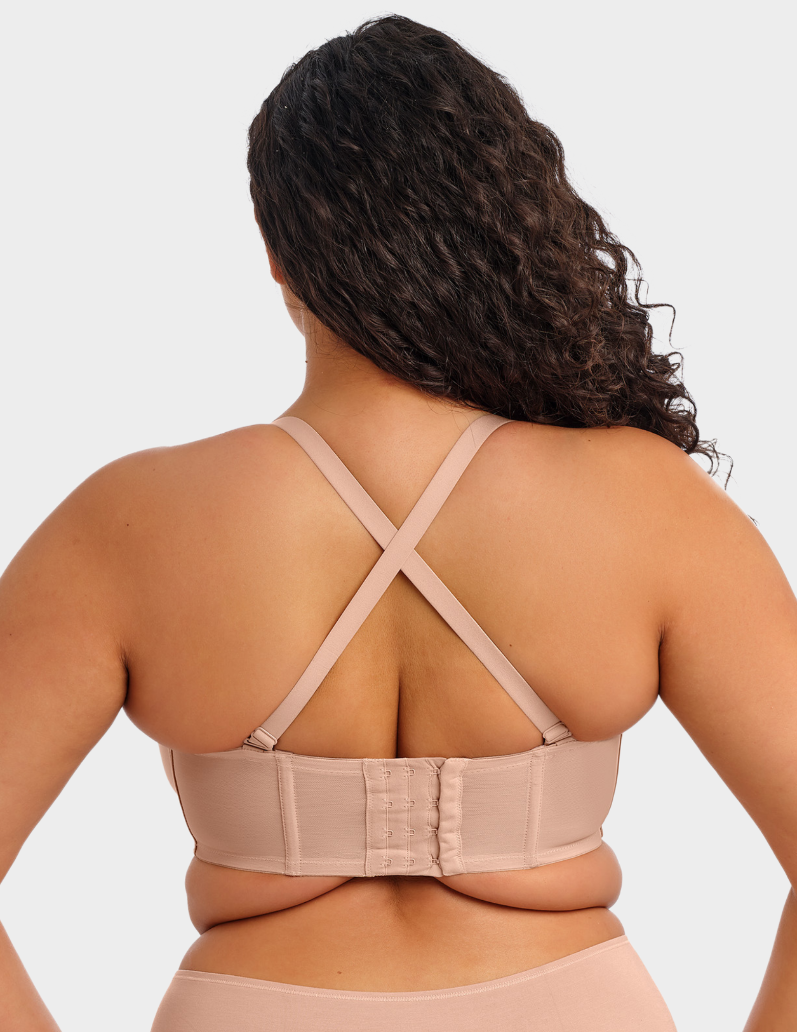 Back view of a model wearing Elomi Smooth strapless bra in Sahara with straps crossed