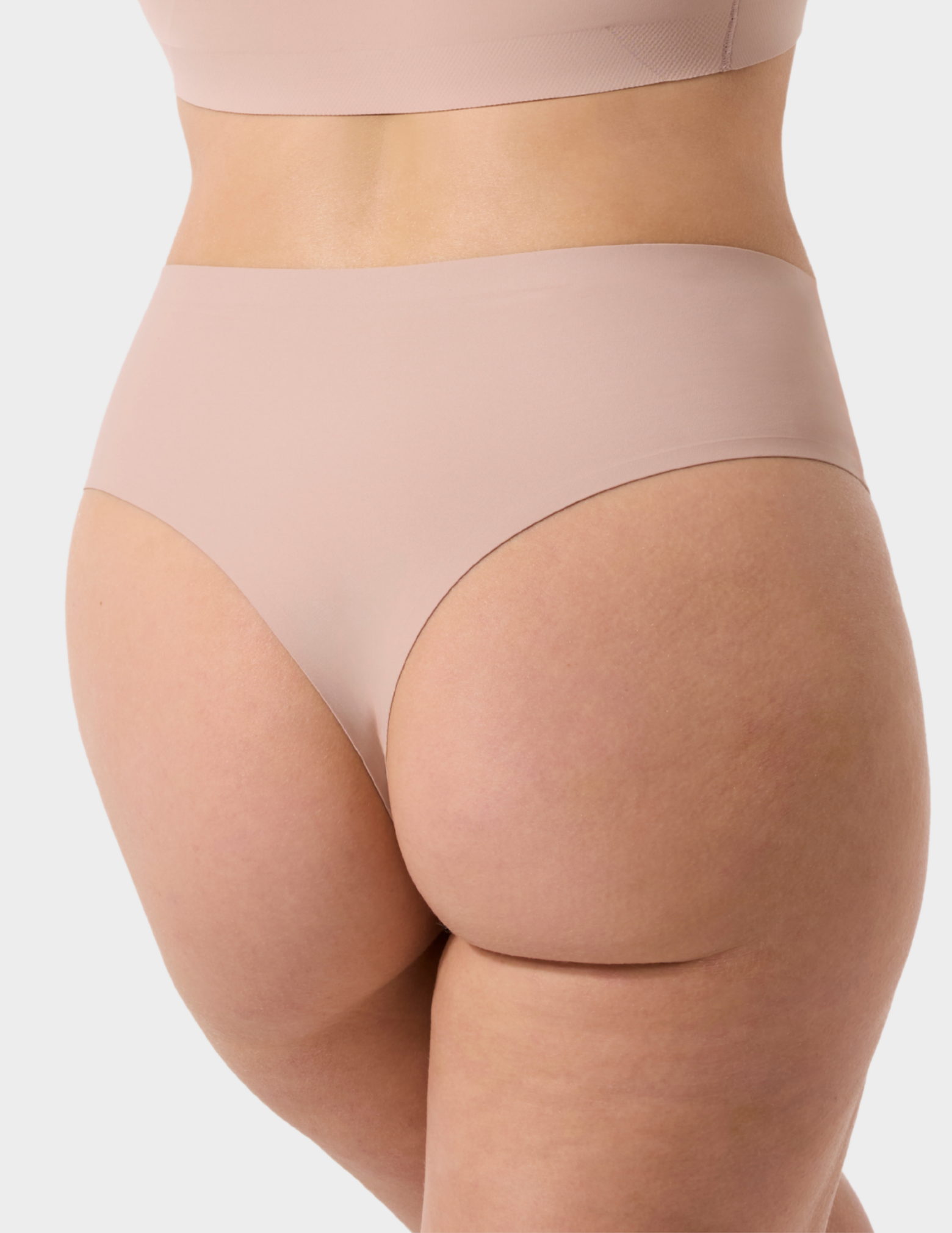 Back view of a model wearing Evelyn & Bobbie Seamless Thong in Petal Drift