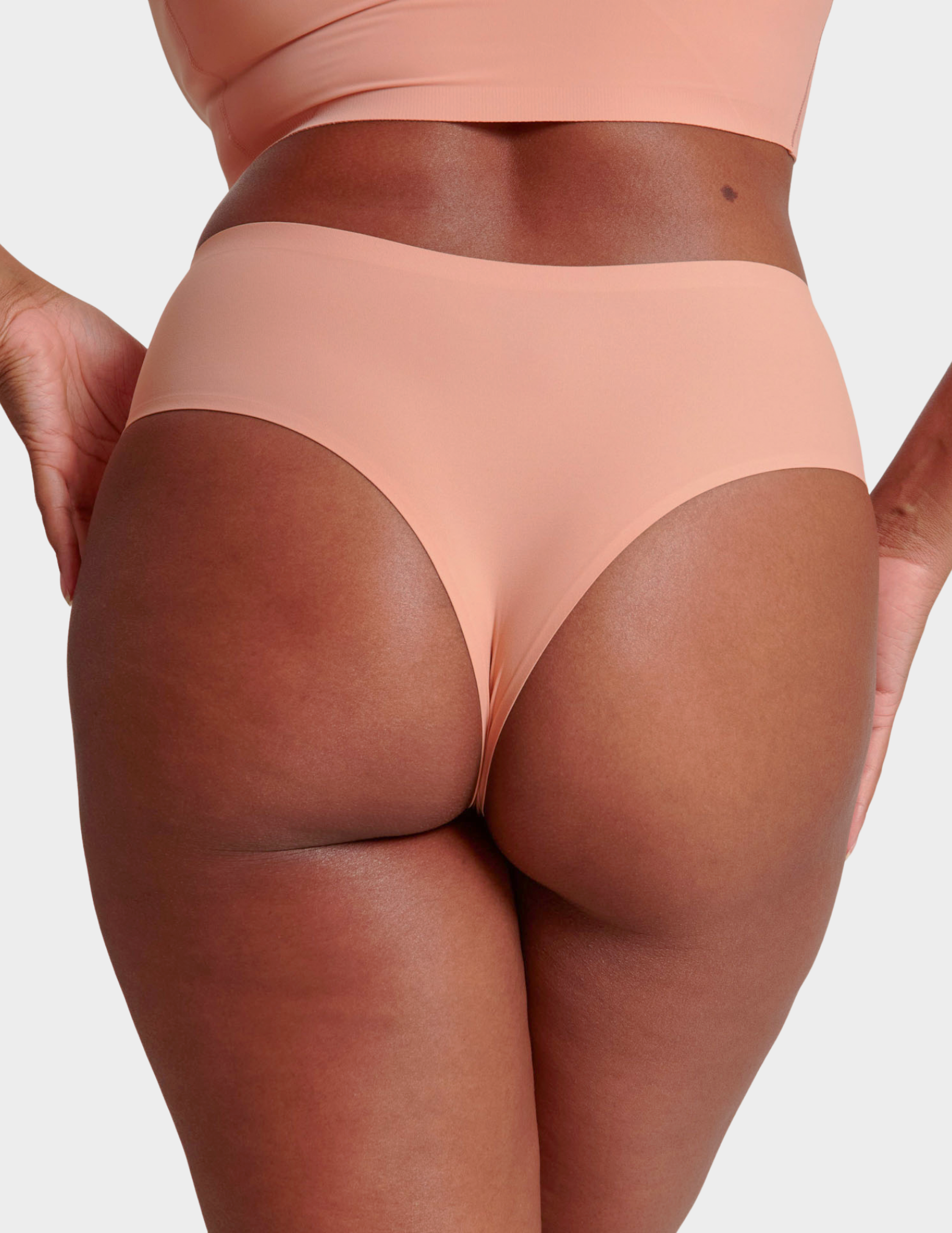 Back view of a model wearing Evelyn & Bobbie Seamless Thong in Himalayan Salt