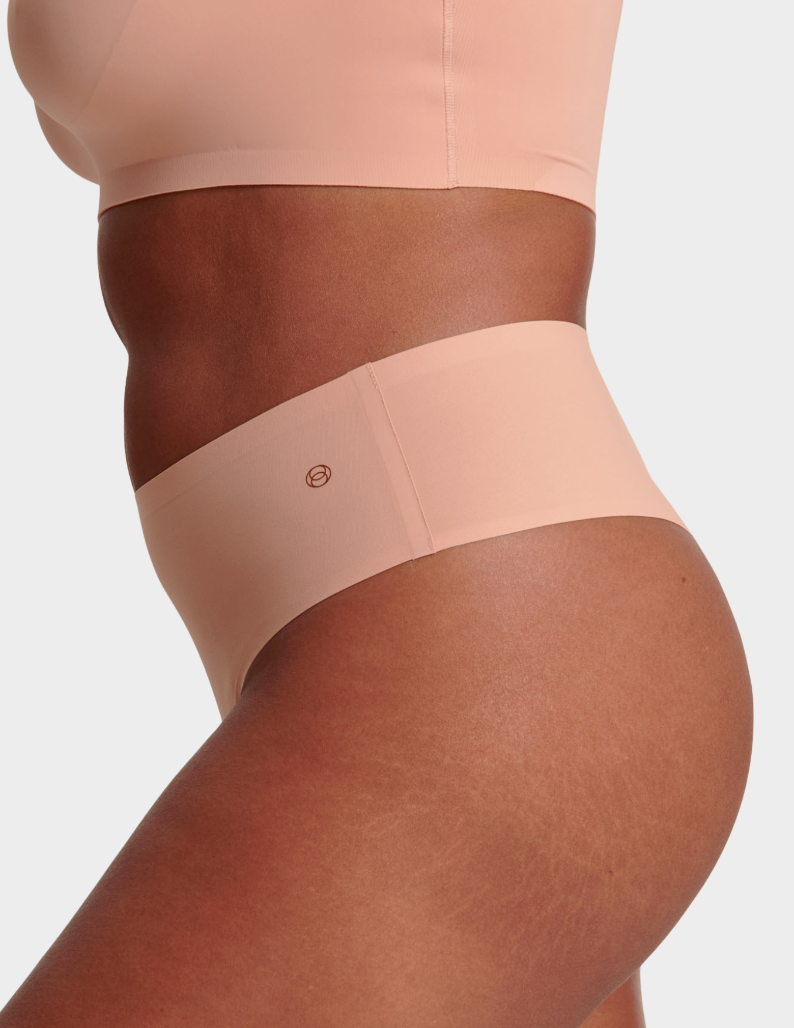 Side view of a model wearing Evelyn & Bobbie Seamless Thong in Himalayan Salt