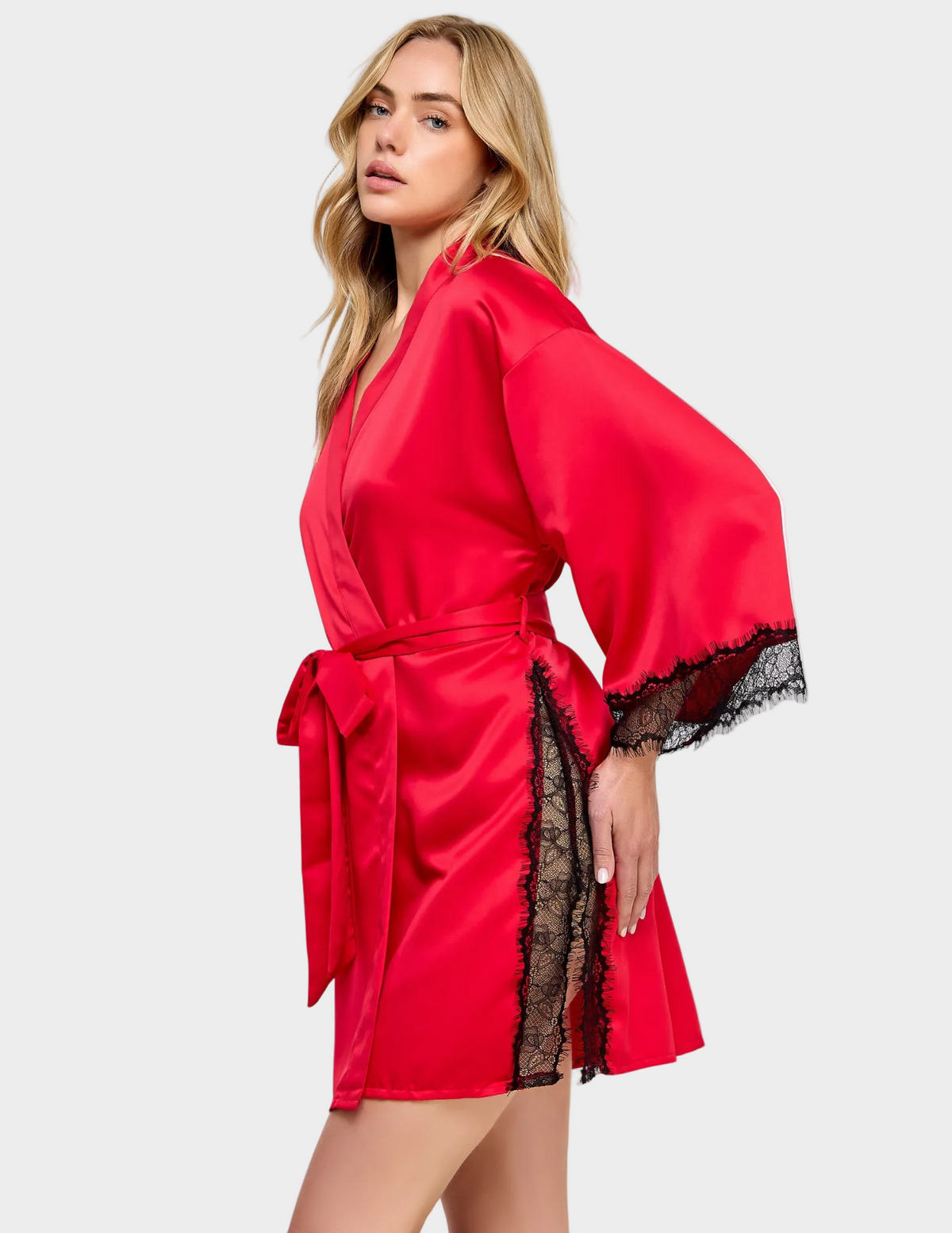 Side view of a model wearing a red satin robe with black lace trim