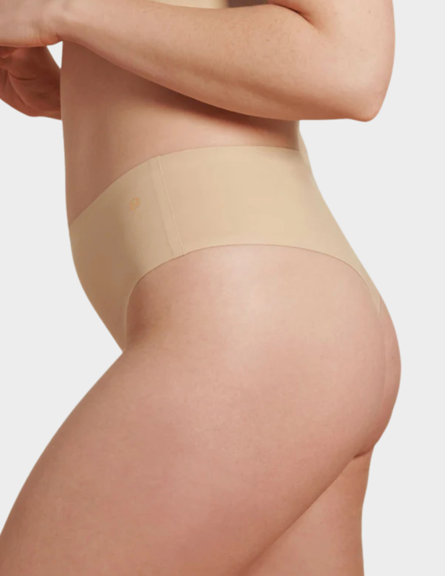 Side view of a model wearing Evelyn & Bobbie Seamless Thong in Sand