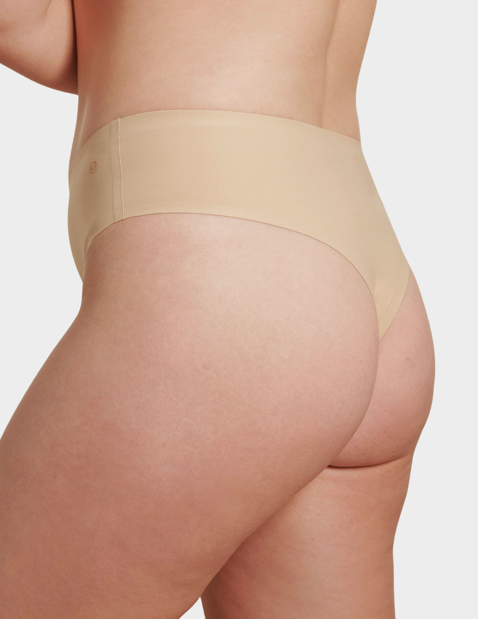 Side view of a model wearing Evelyn & Bobbie Seamless Thong in Sand