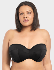 Front view of a model wearing Elomi Essentials bandeau bikini top in black without straps
