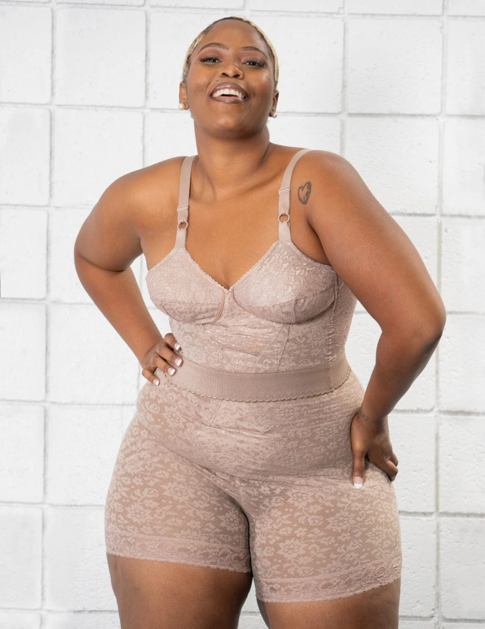 Woman wearing a brown shapewear against a white tiled wall.