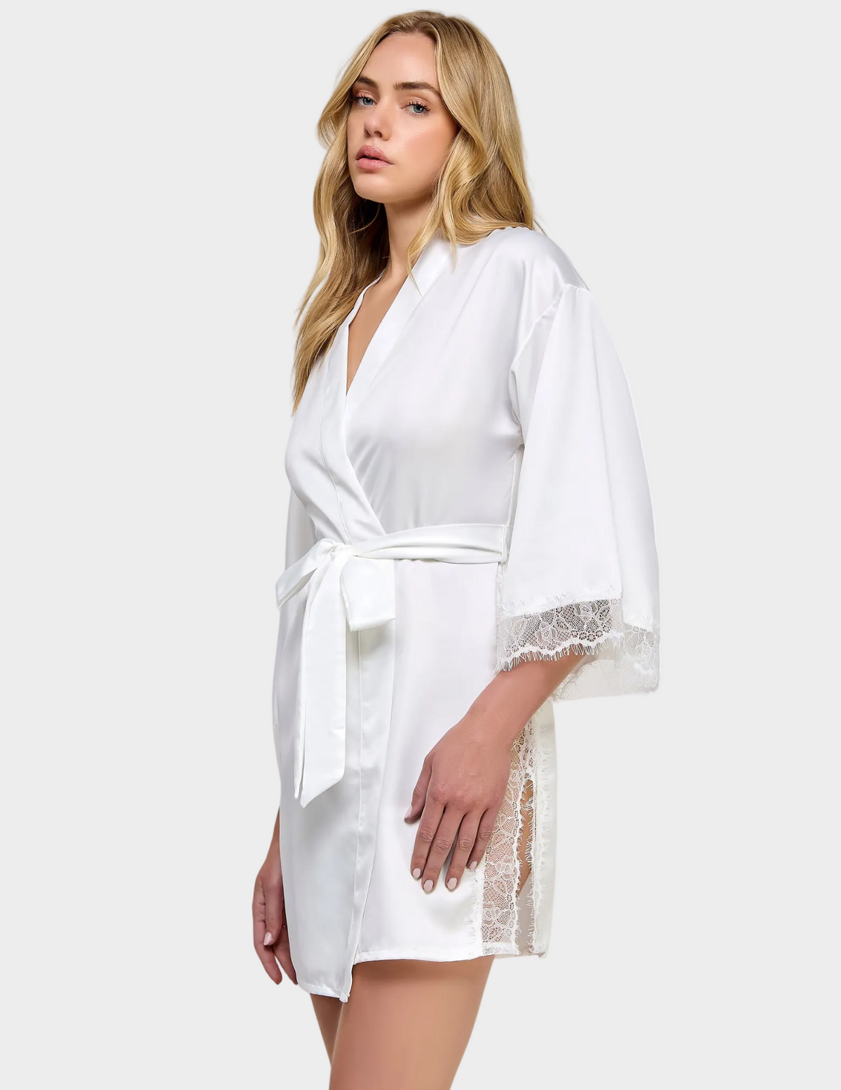 Side view of a model wearing a white satin robe with lace trim