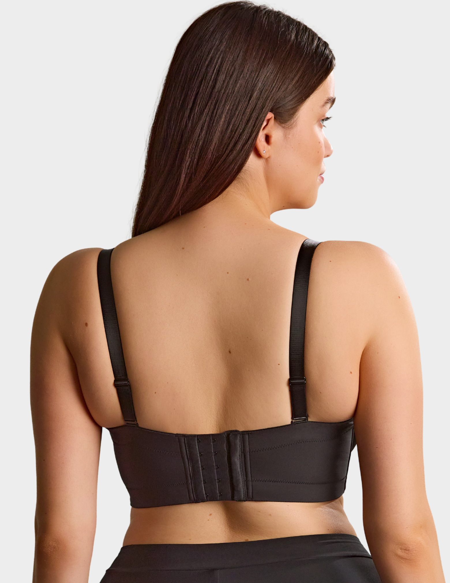Back view of a model wearing Sculptresse Dana strapless bra in Black with straps