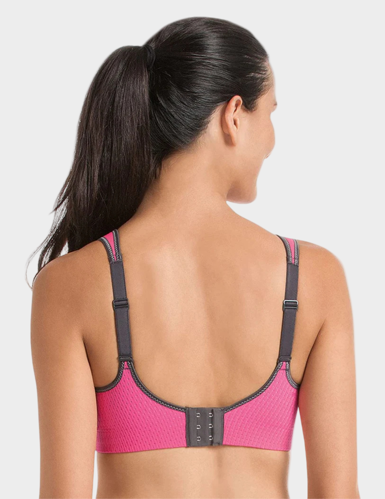 Woman wearing a pink sports bra with grey accents on a white background