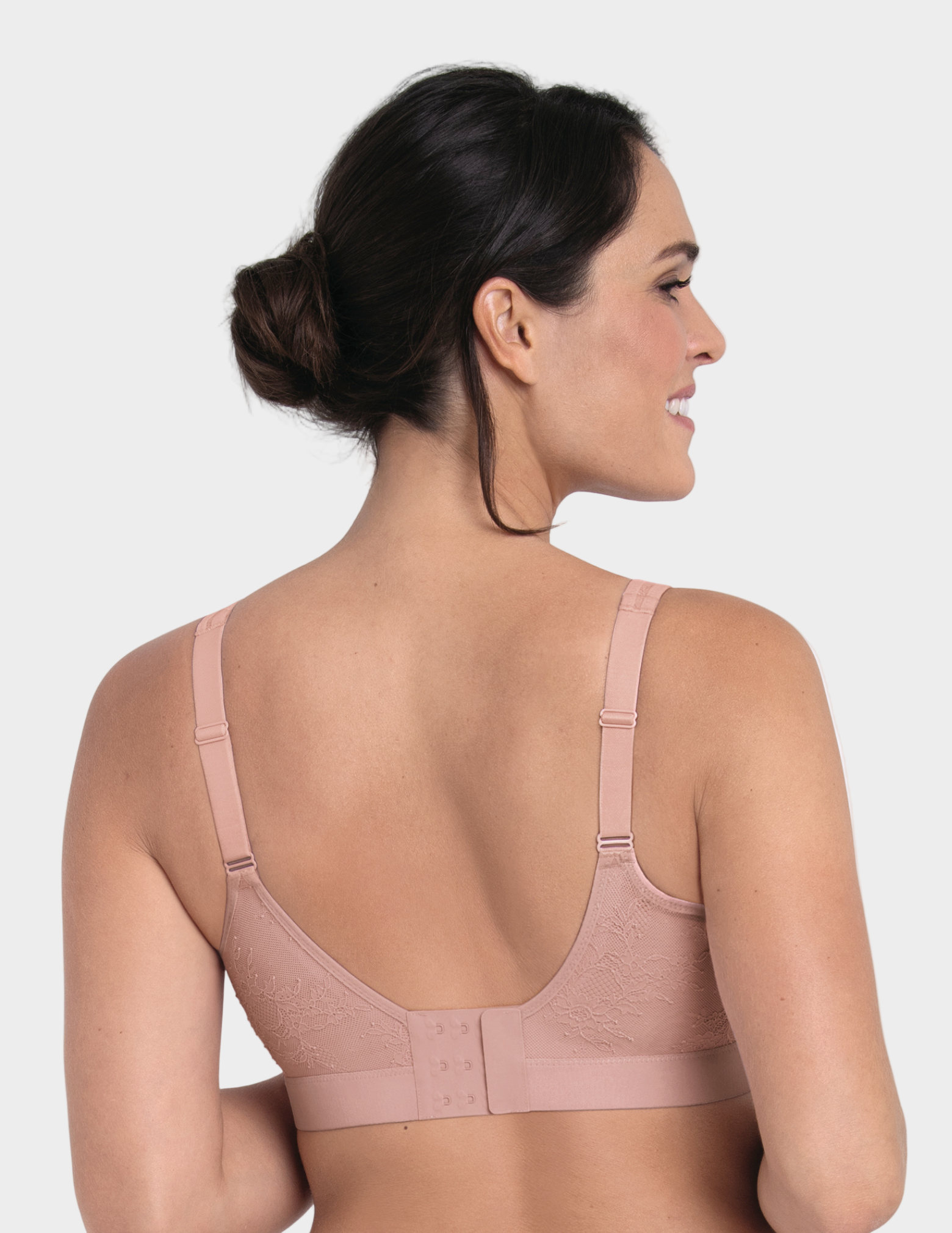 Woman wearing a light pink bra on a white background