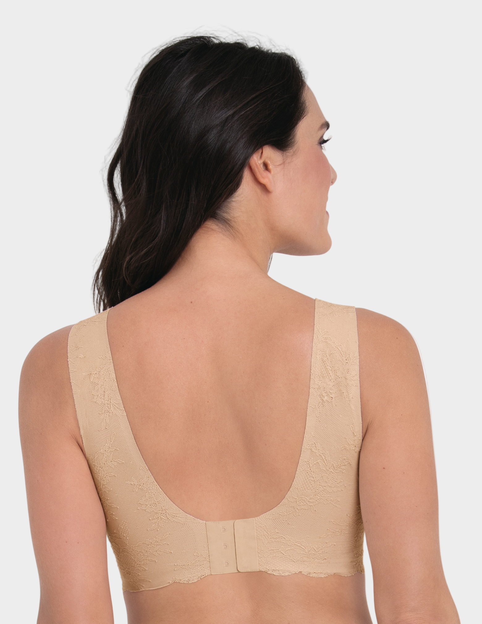 Woman wearing a beige lace bralette on a white background