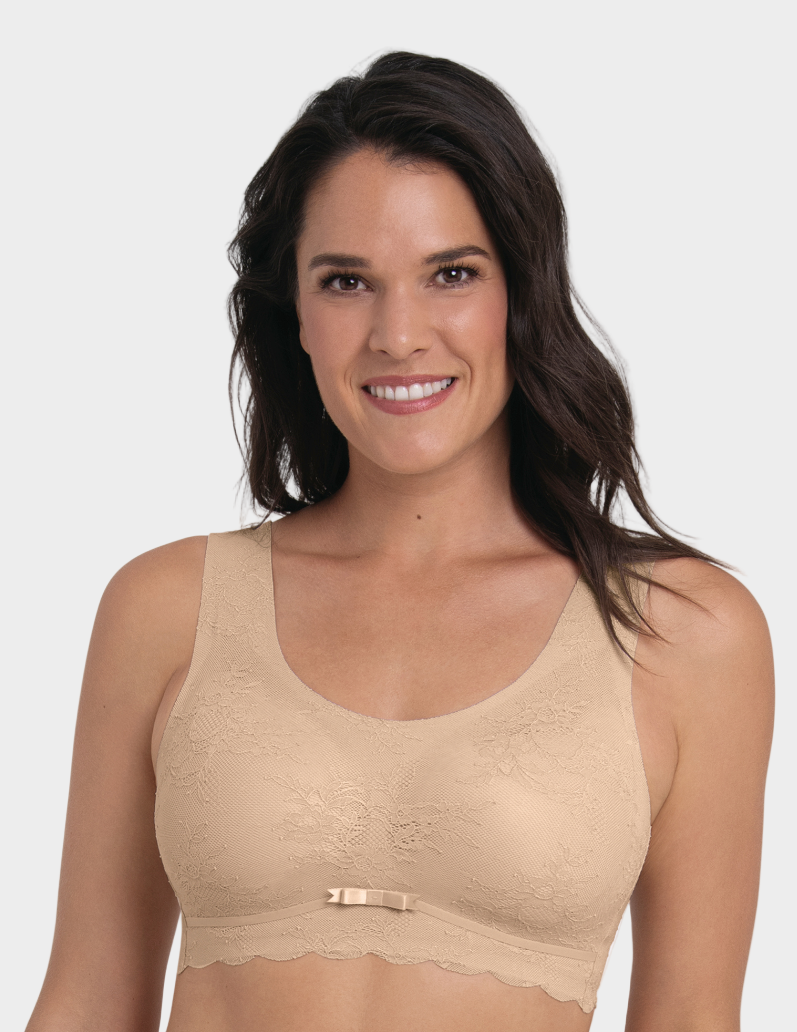 Woman wearing a beige bralette against a plain background