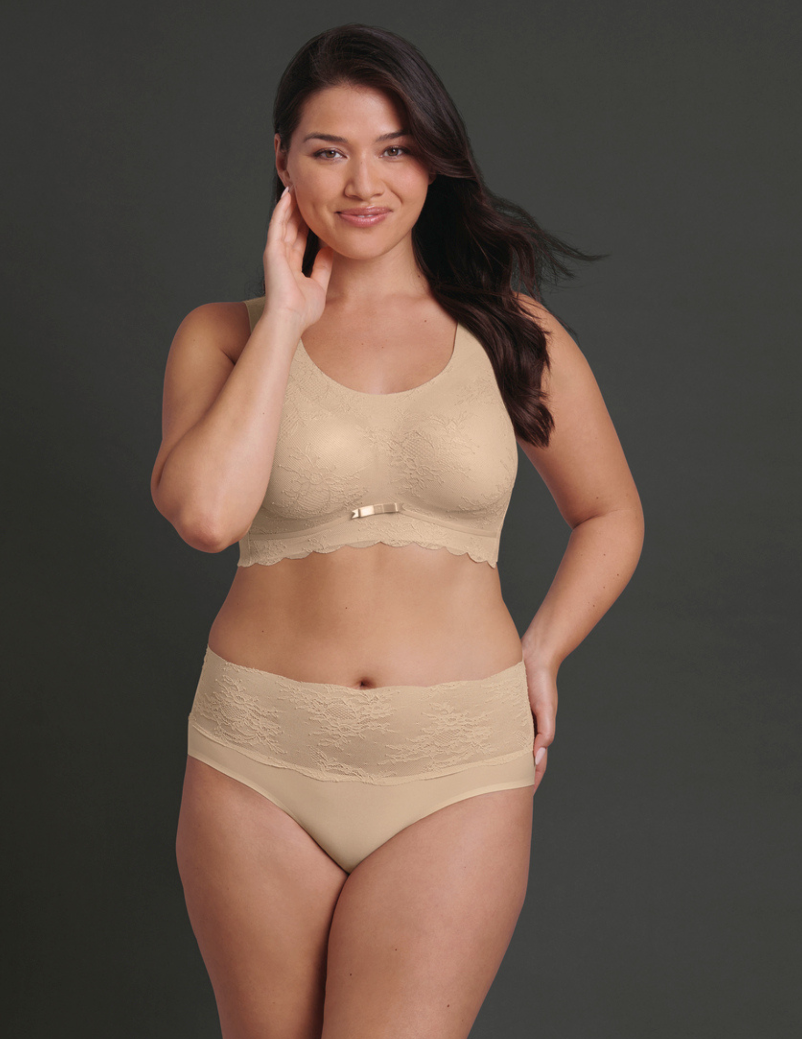 Woman wearing beige lingerie against a dark background