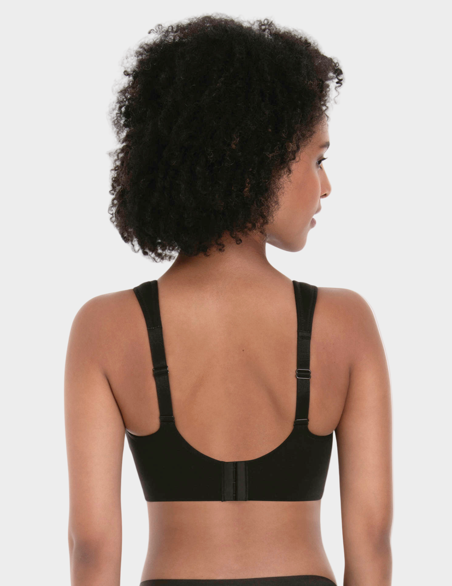 Woman wearing a black bralette on a plain background