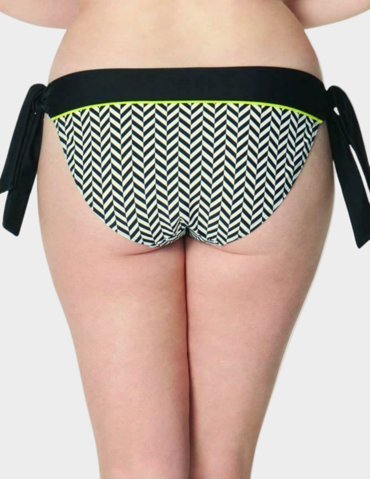 back view of woman wearing black and white geometric print swim bottom with green accent and black tie sides