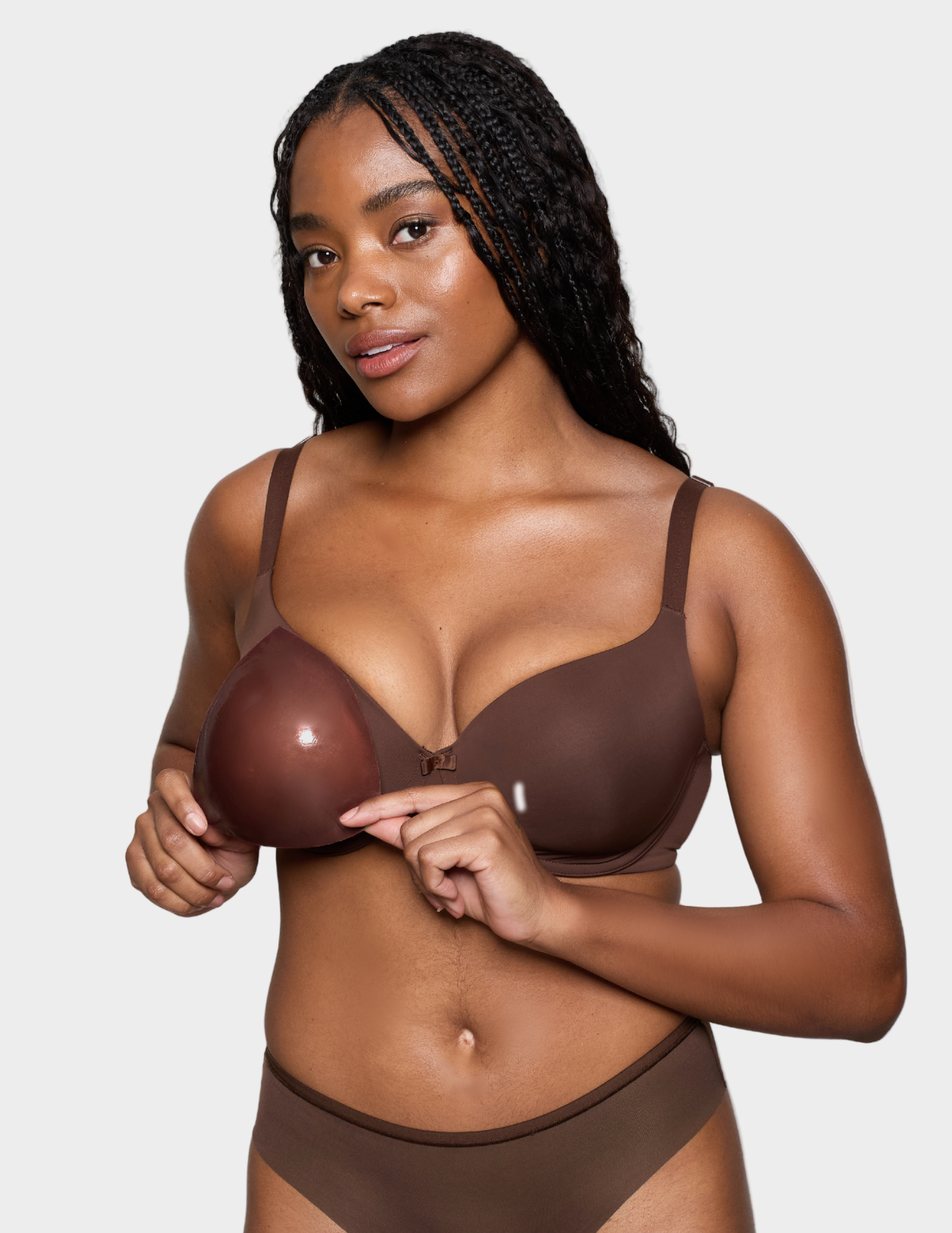Woman wearing a brown bra and panties holding brown bra insert