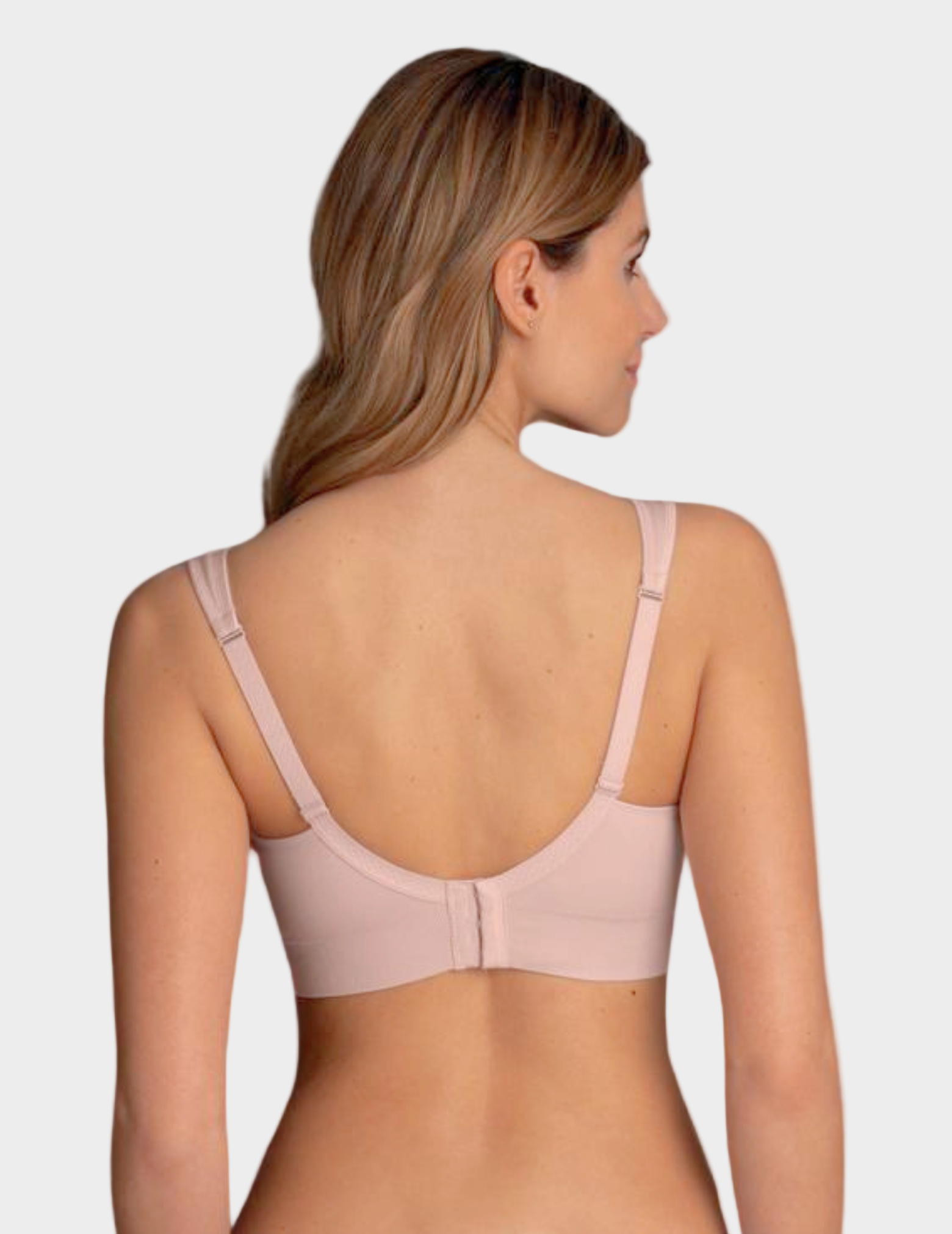 Woman wearing a light pink bralette against a white background