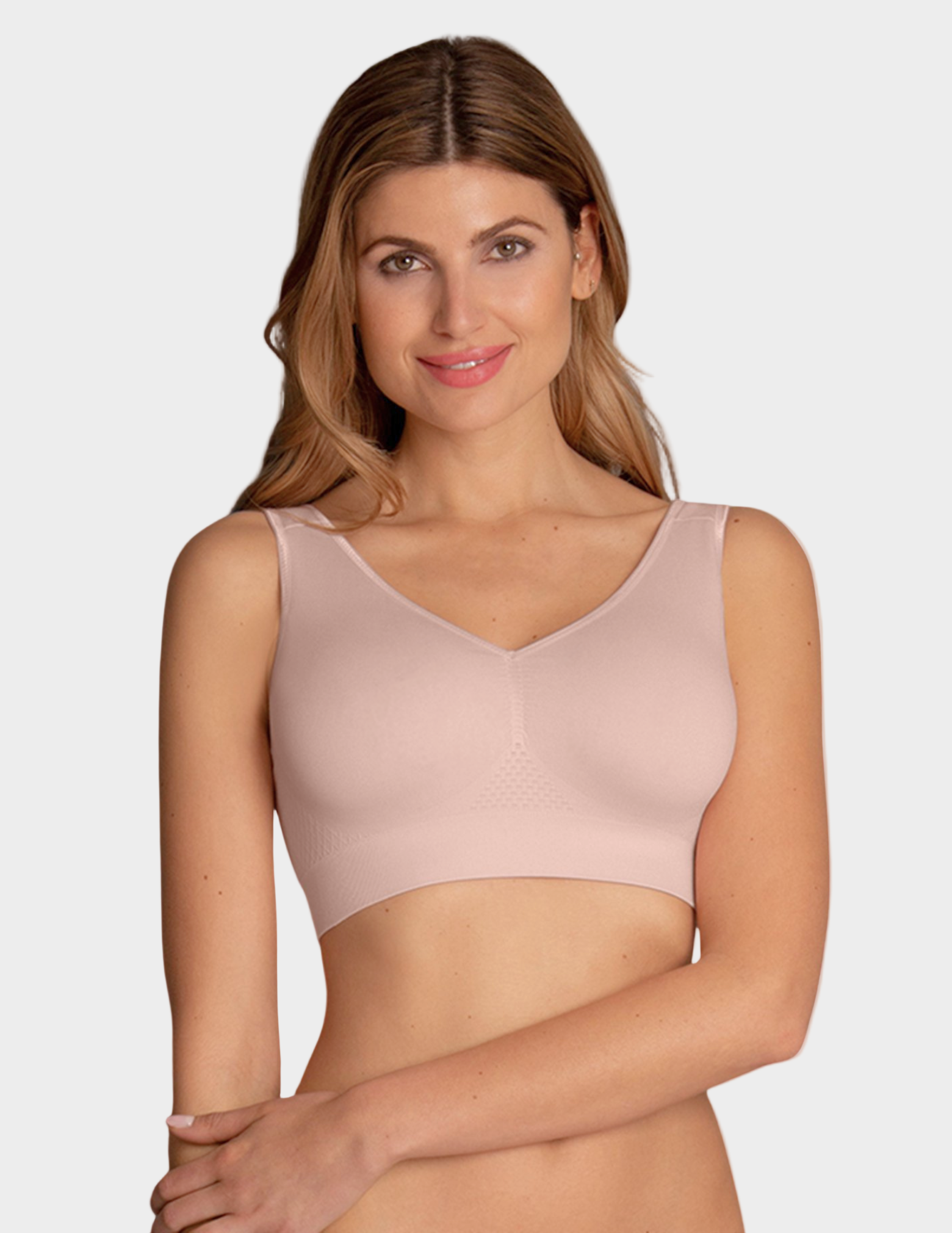 Woman wearing a light pink bralette against a plain background