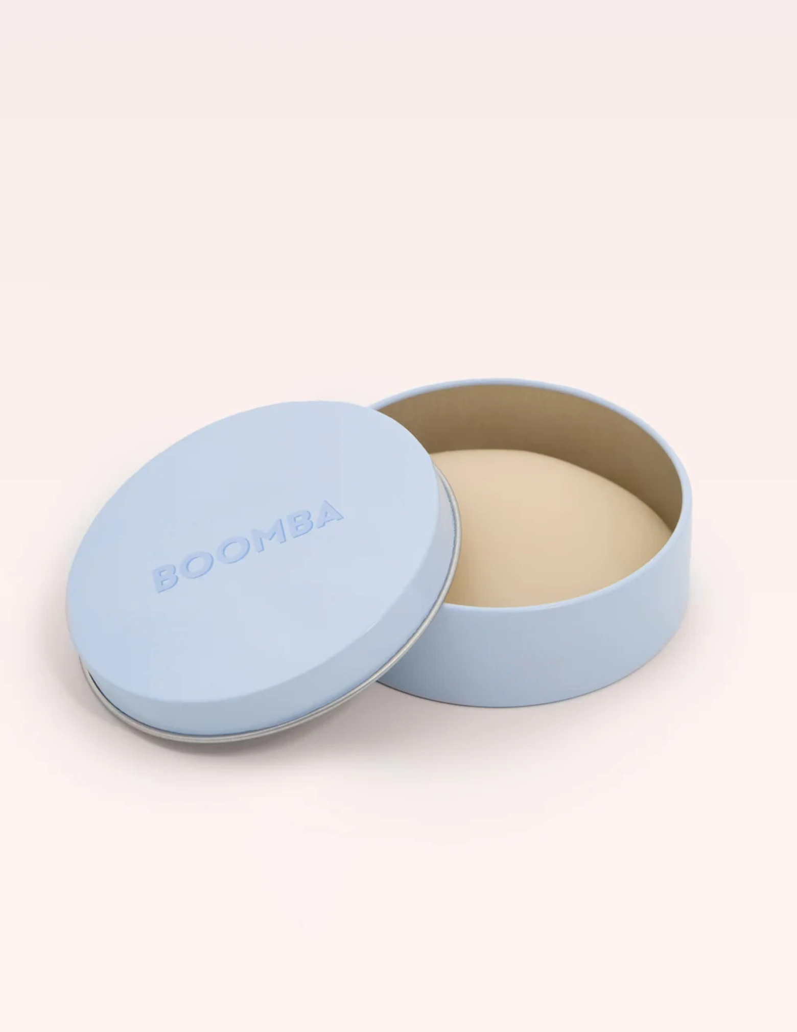 round blue container labeled BOOMBA with light beige nipple cover inside