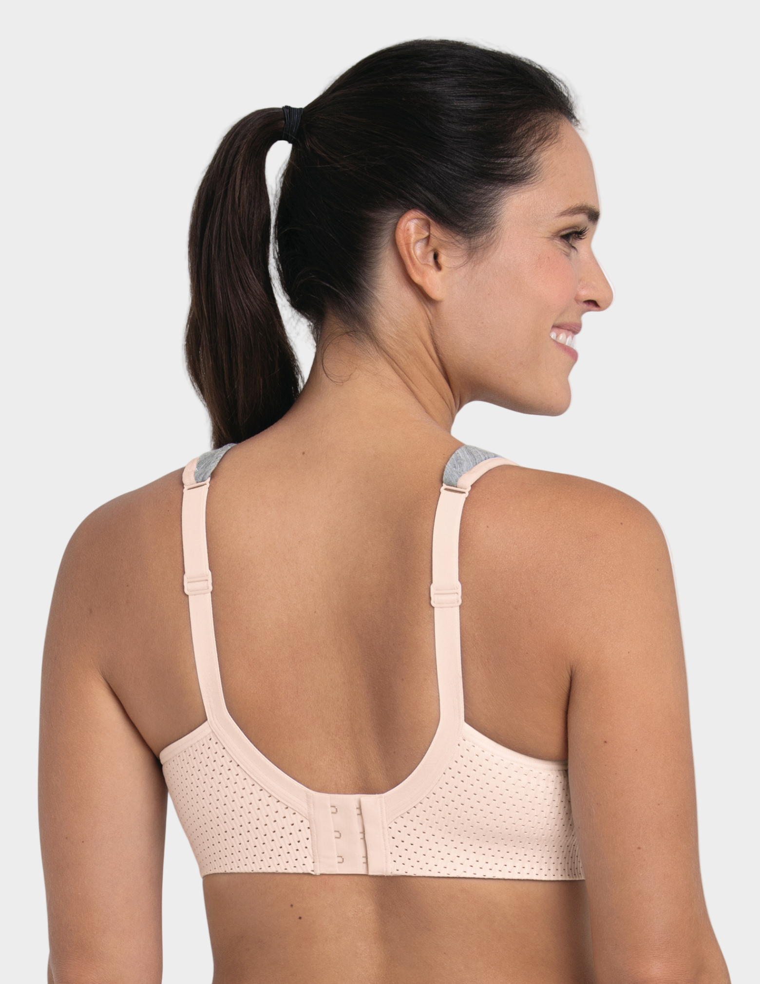 back view of Woman wearing a beige sports bra on a white background
