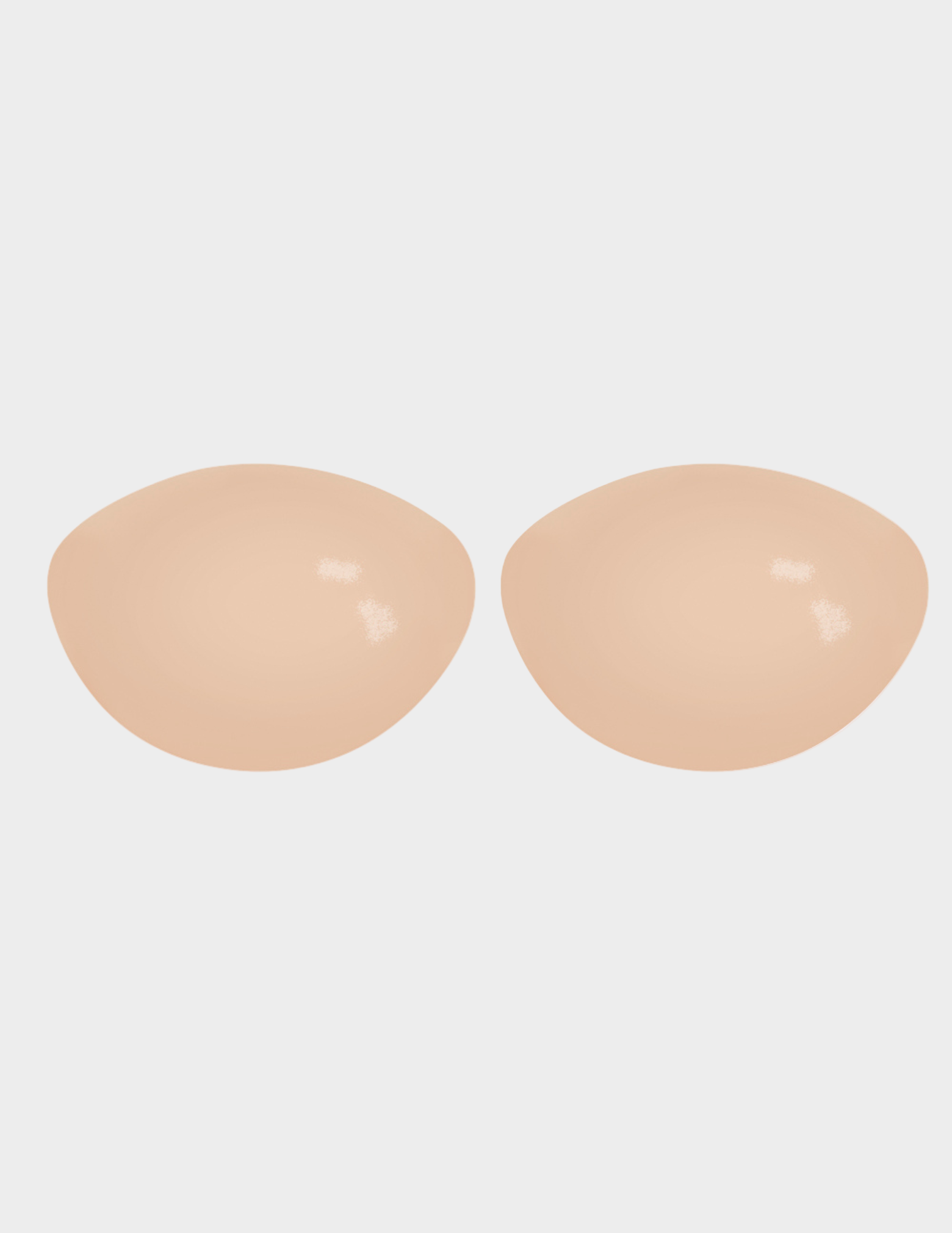 Beige silicone bra pads on a white background