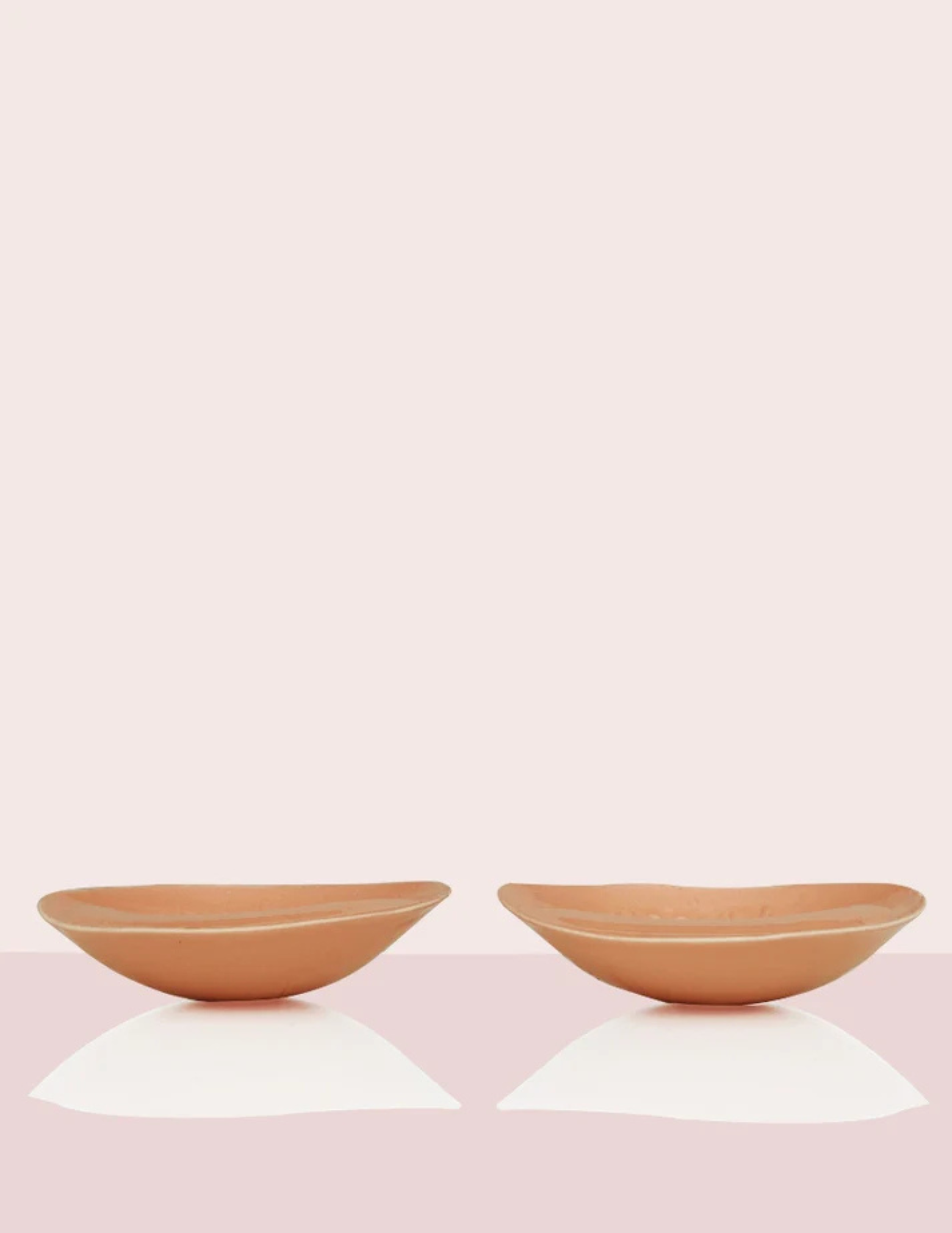 side view of two tan colored padded bra inserts laying on table