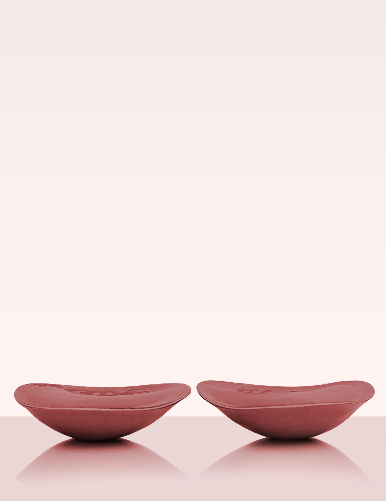 side view of two brown padded bra inserts laying on table