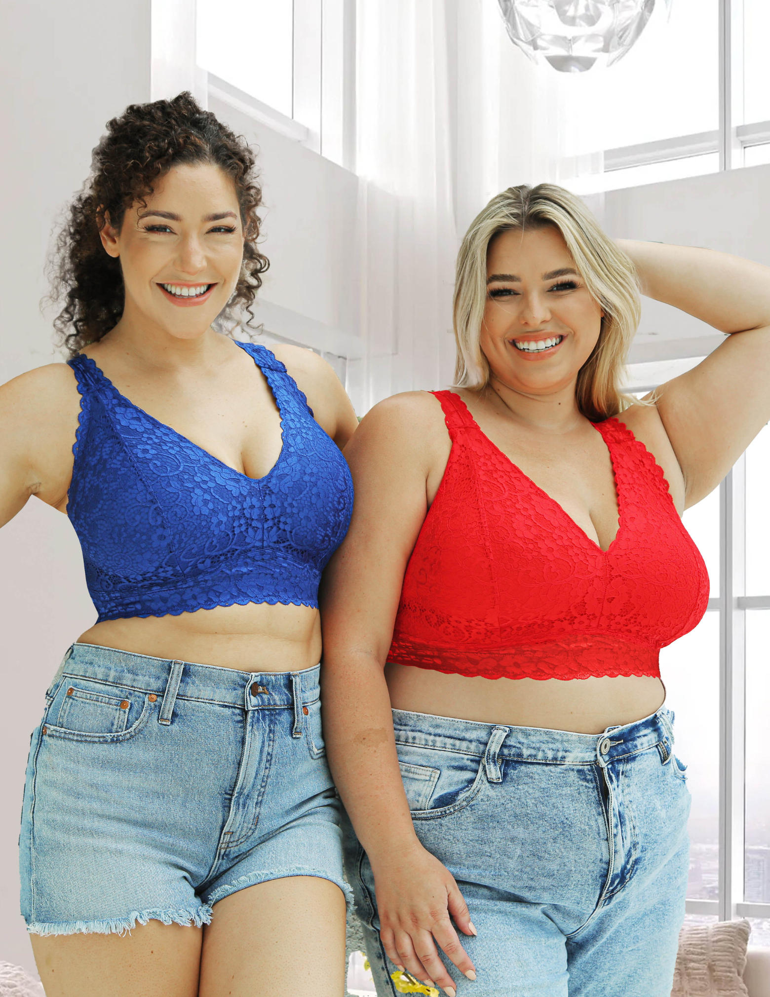 Two women wearing red and blue lace bralettes and jeans indoors.