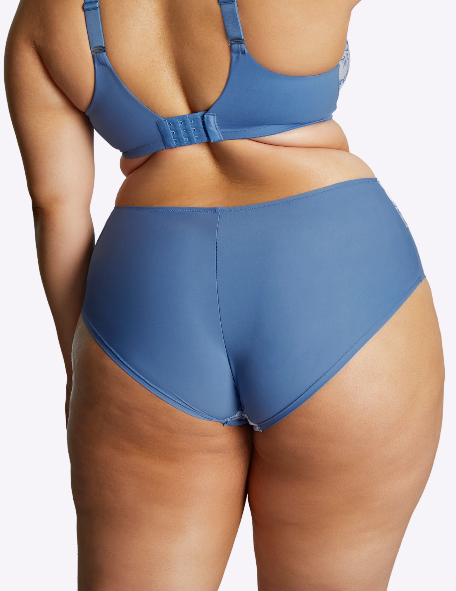 back view of model wearing bliss brief in blue floral—the back fabric is an opaque blue