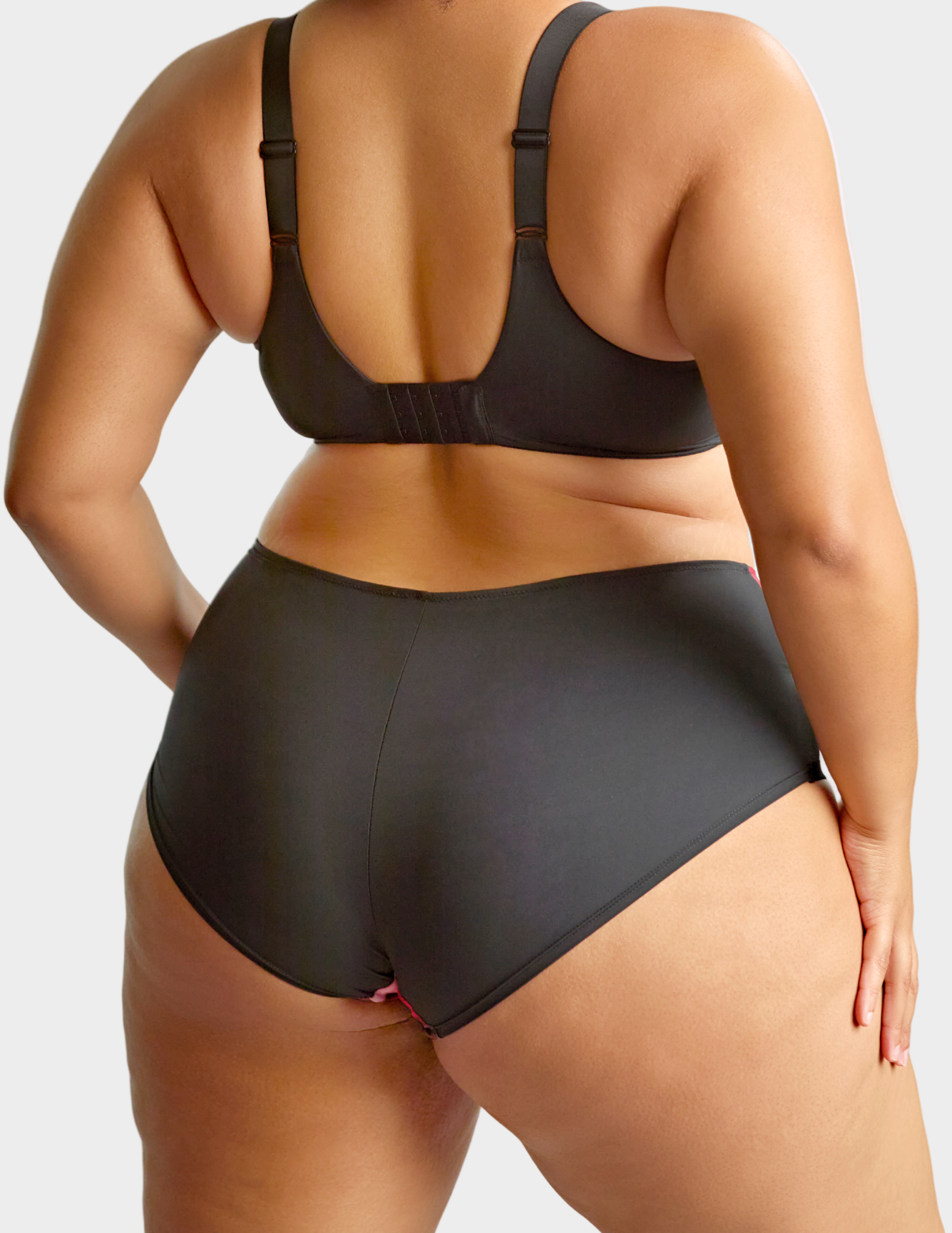 Back view of model wearing bliss brief in rose print—the back fabric is an opaque black
