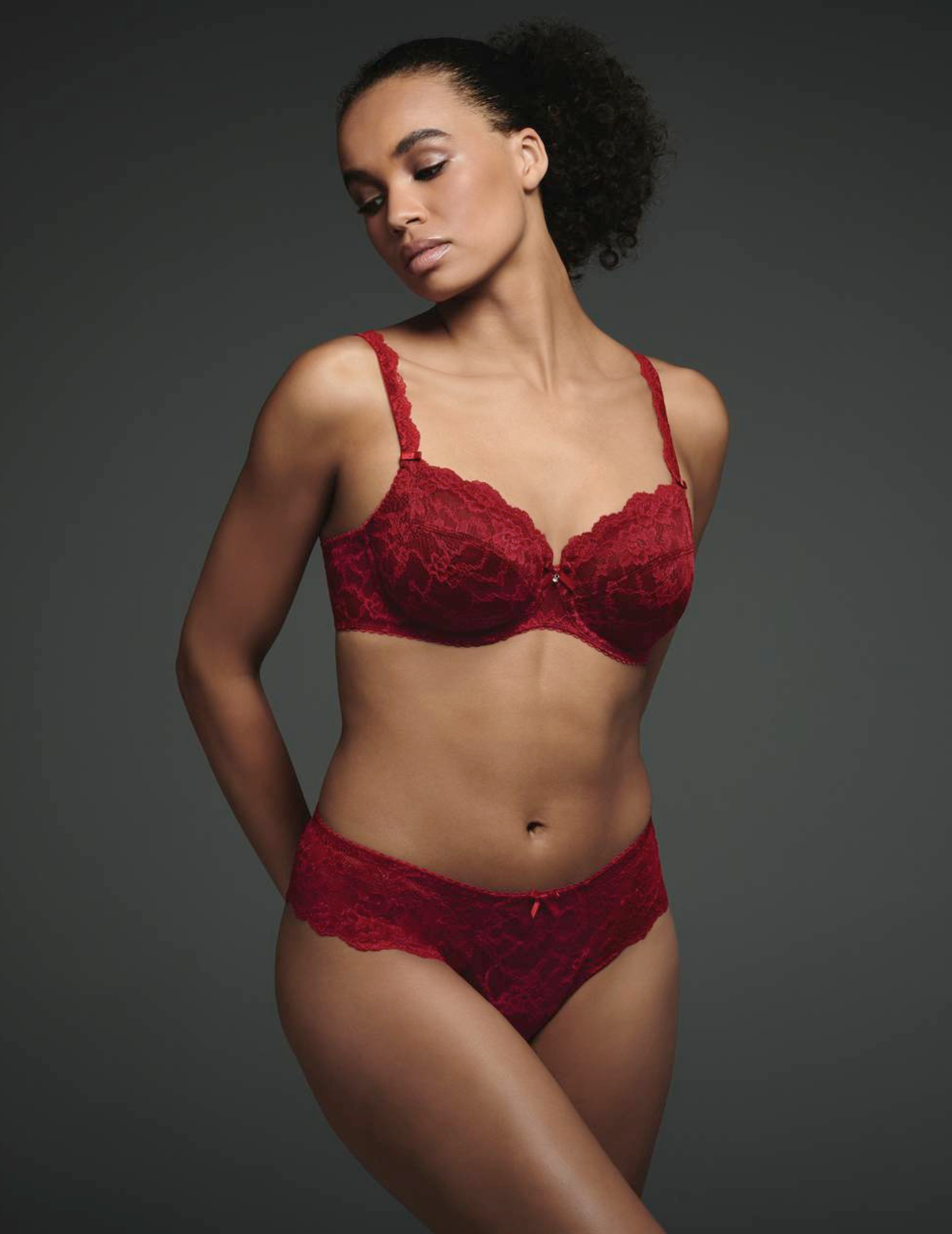 Woman wearing a red lace lingerie set against a dark background