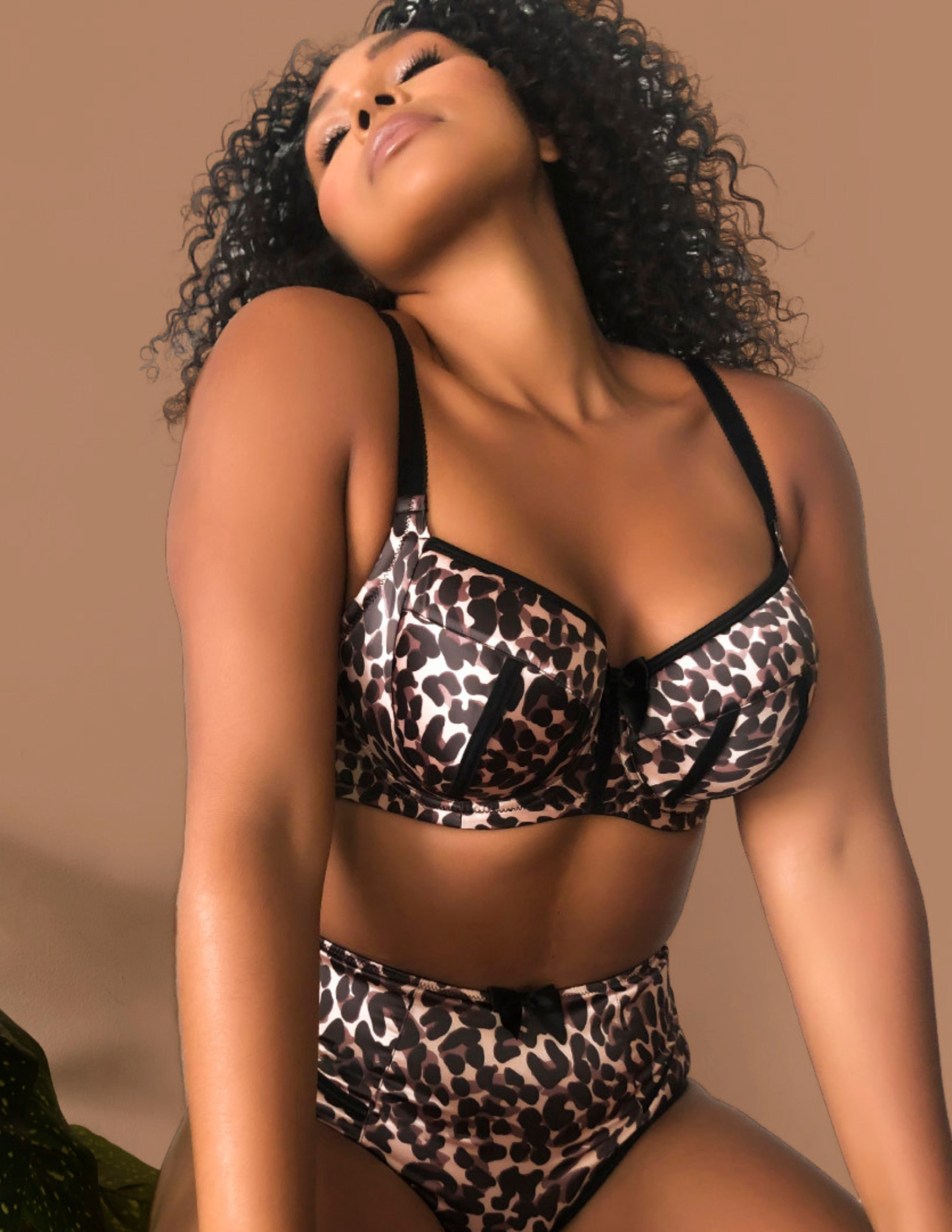 Woman wearing a leopard print lingerie set against a beige background