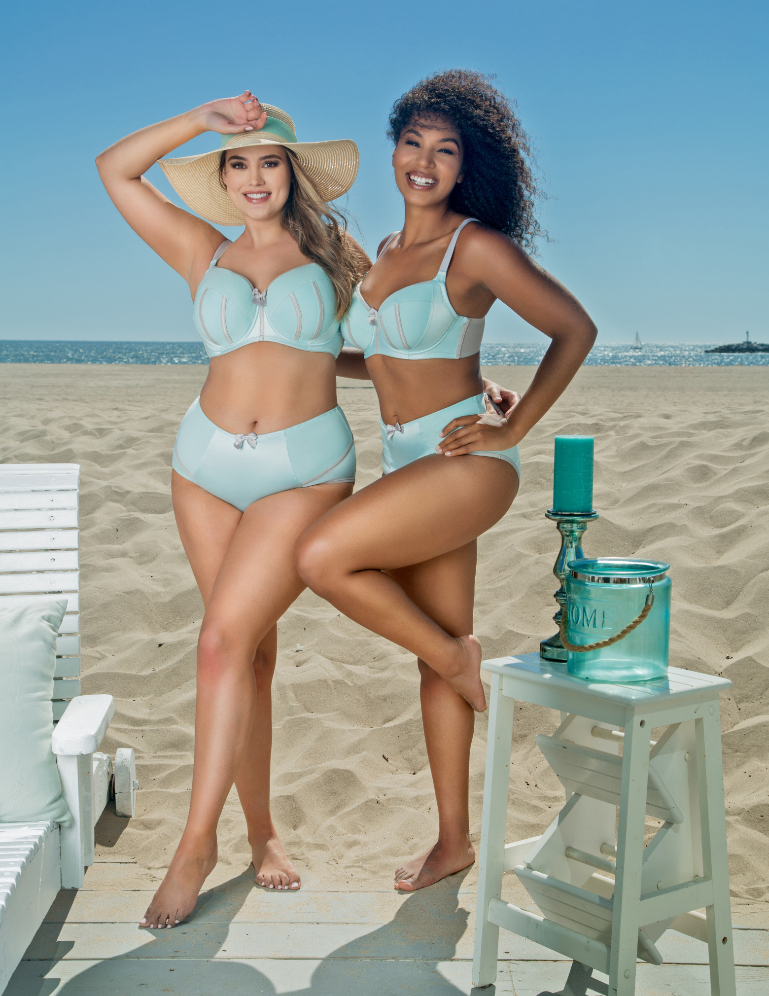 Two women wearing Charlotte lingerie set in seaglass green posing on a beach