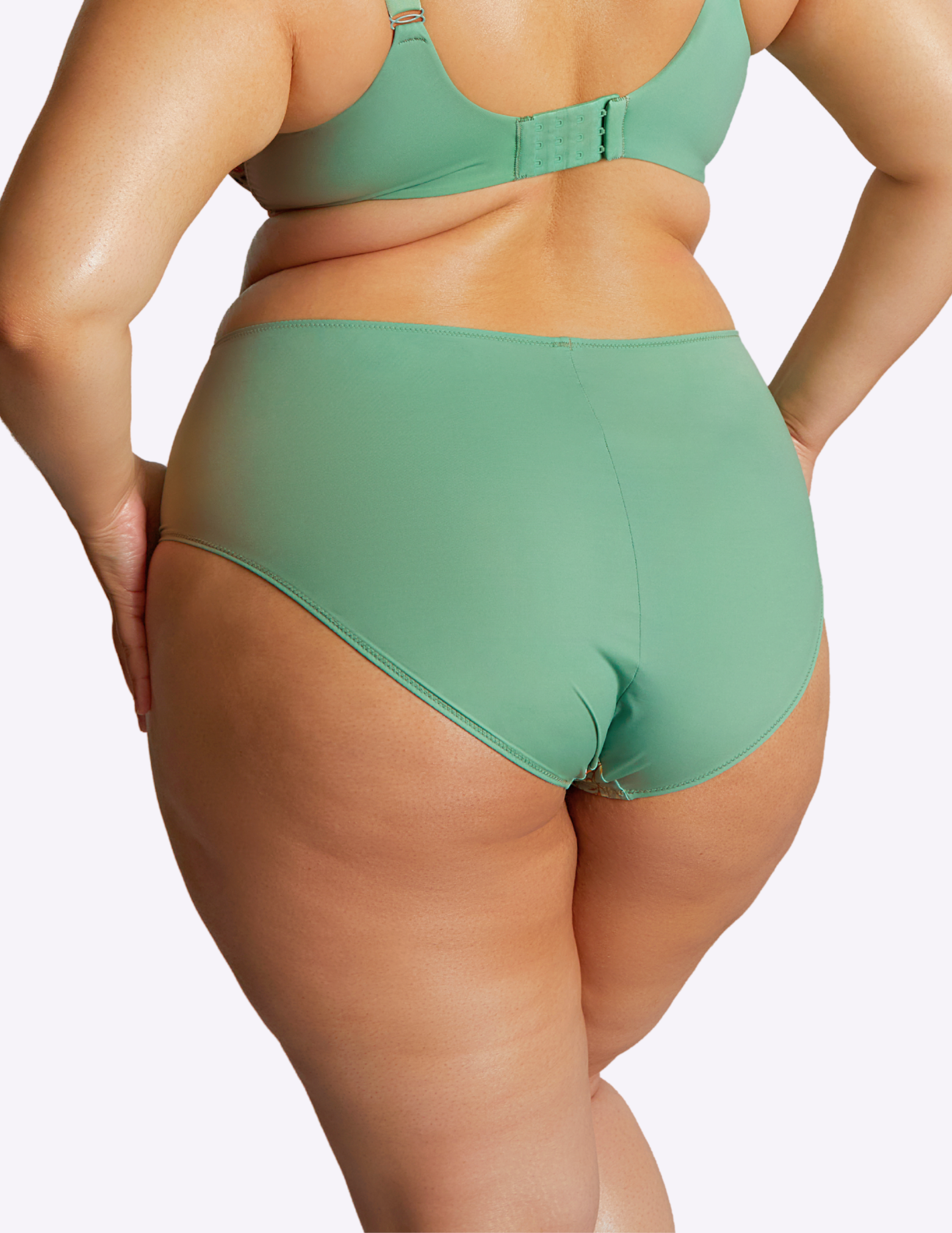 Back view of model wearing Esme brief in wonderland—the back fabric is solid green
