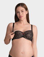 Woman wearing a black lace nursing bra on a plain background