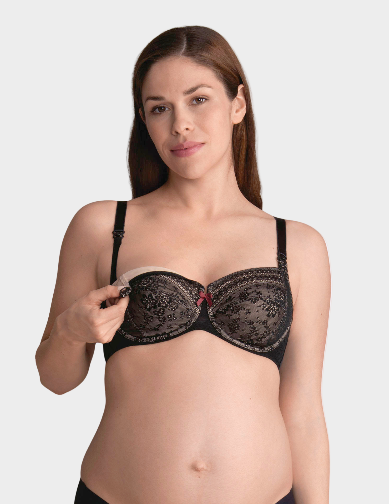 Woman wearing a black lace nursing bra on a plain background