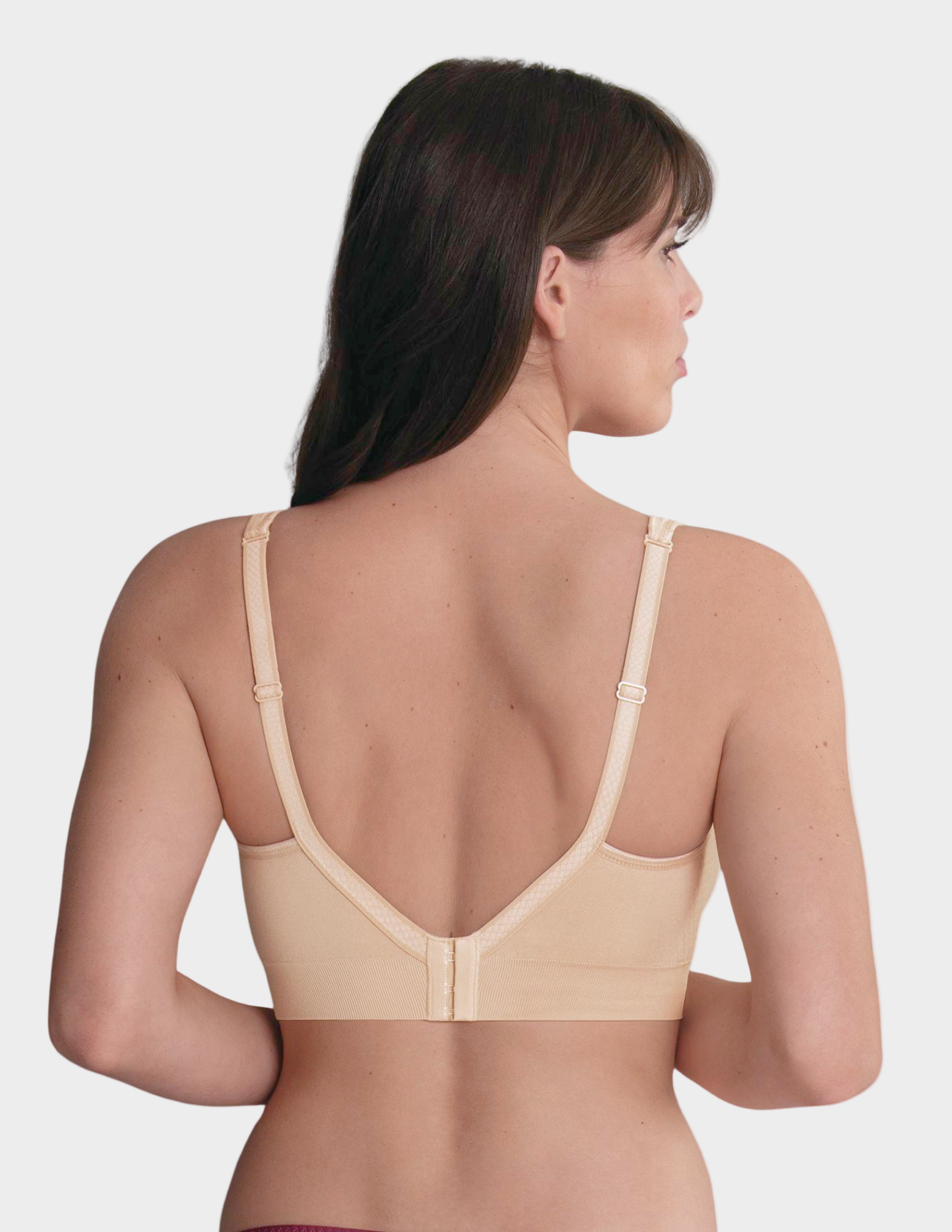 Woman wearing a beige bralette on a white background