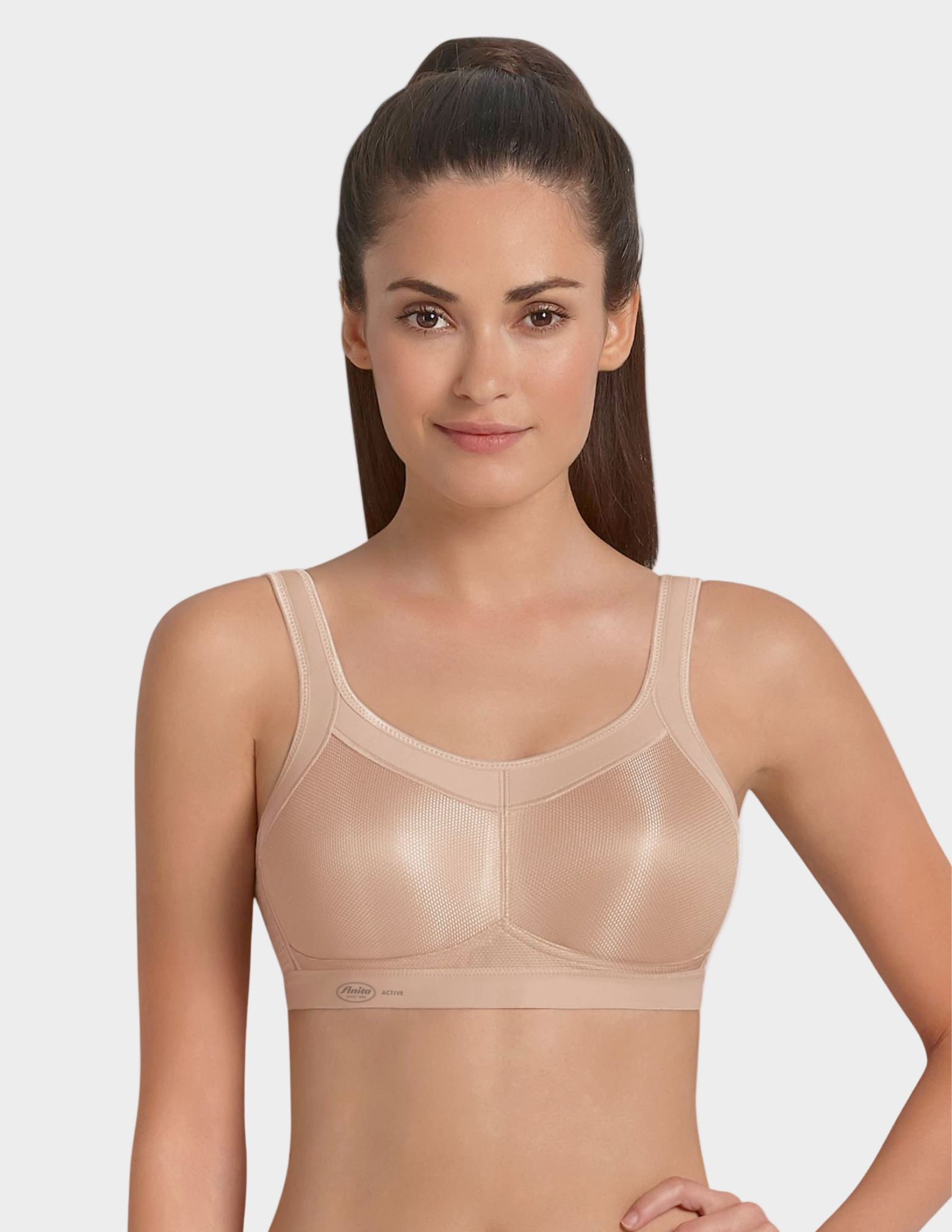 front view of Woman wearing a beige sports bra against a plain background