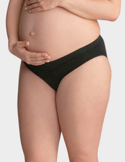 Pregnant woman wearing black maternity underwear on a plain background
