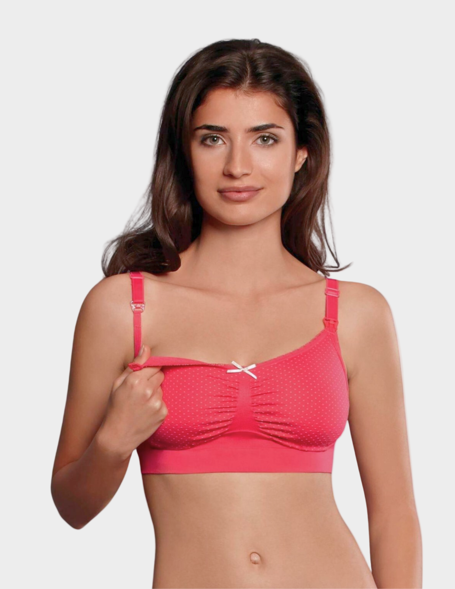 Woman wearing a pink polka dot nursing bra against a white background