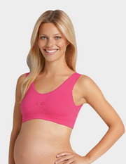 Woman wearing a pink polka dot maternity bra on a white background