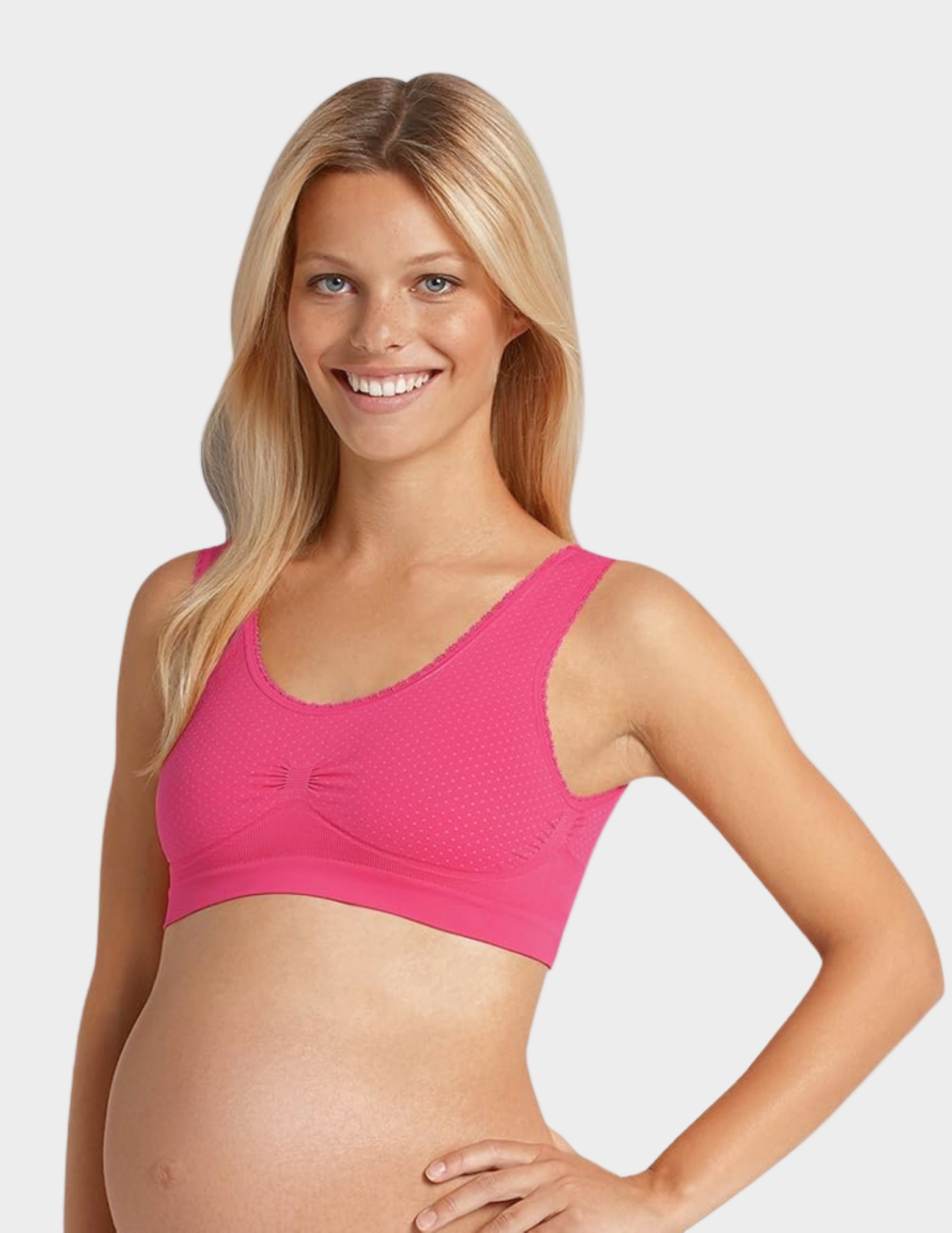 Woman wearing a pink polka dot maternity bra on a white background