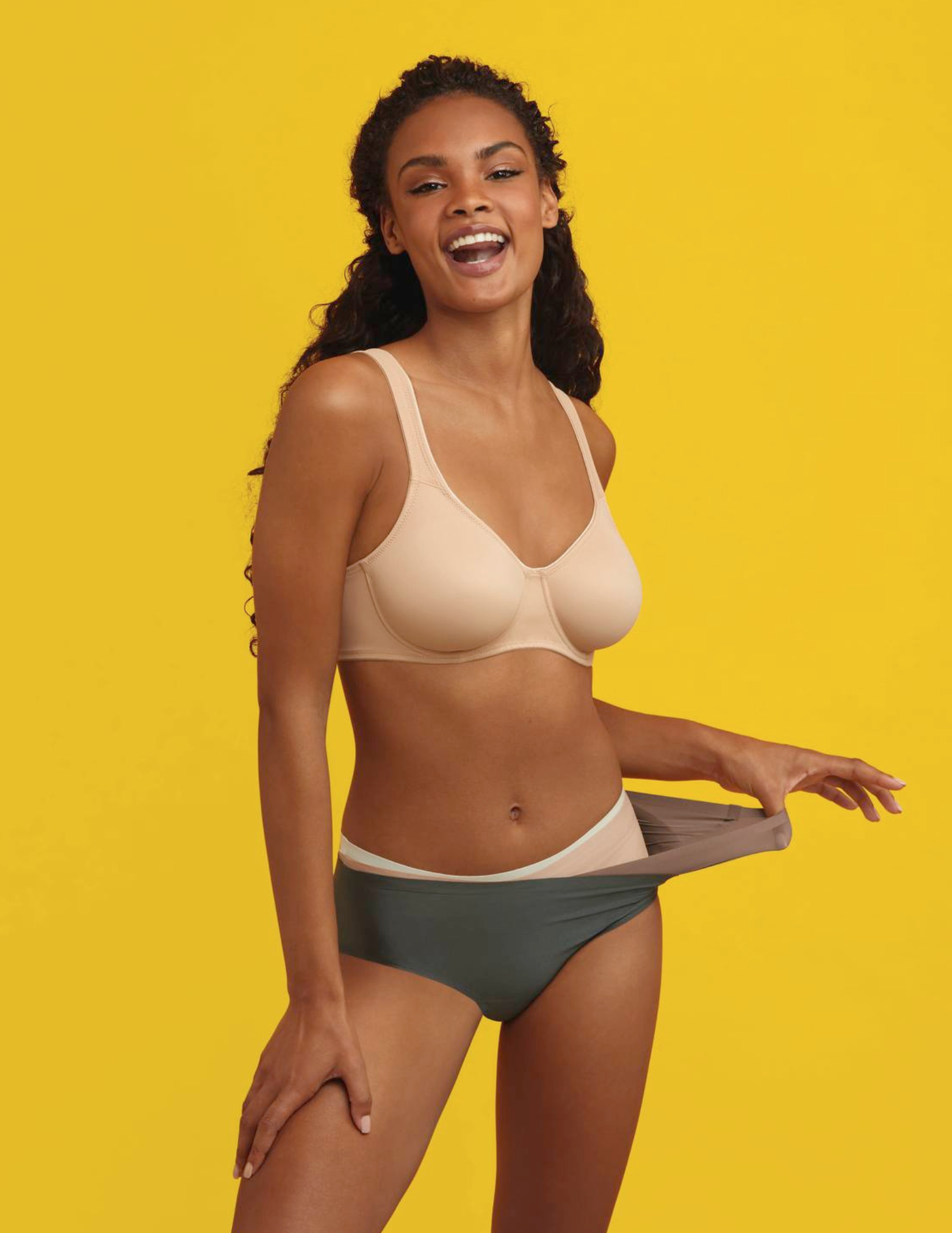 Woman wearing a beige bra and green underwear on a yellow background